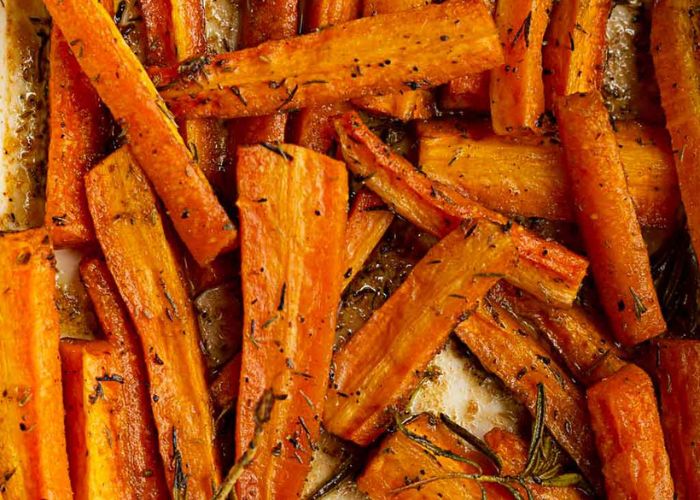 Bastones de zanahoria dorados en una bandeja de horno con pimentón y sal