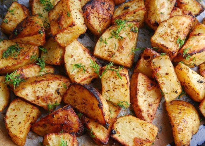 Cuñas de batata doradas con hojas de romero sobre papel manteca