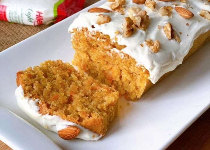 Budín de zanahoria integral decorado con nueces picadas sobre una mesa de madera