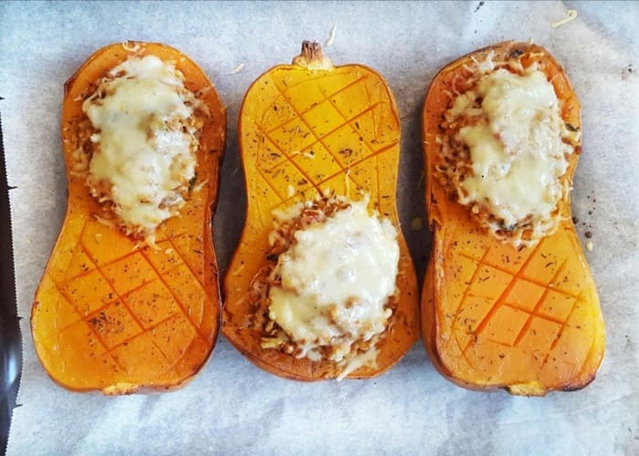 Zapallo anco relleno de quinoa y espinaca, decorado con nueces en una tabla de madera
