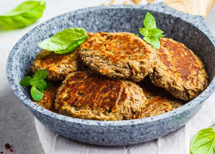 Hamburguesas de lentejas doradas en sartén con guarnición de hojas verdes