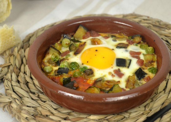 Cazuela de barro con huevos, pimientos rojos y tomates cherry asados