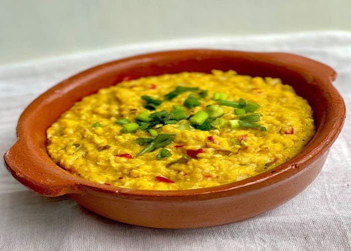 Plato de humita en olla argentina decorado con albahaca fresca