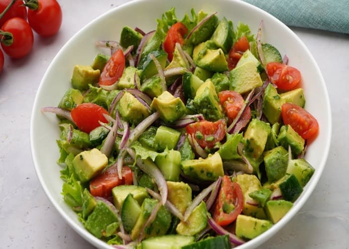 Láminas de palta fresca sobre espinacas orgánicas