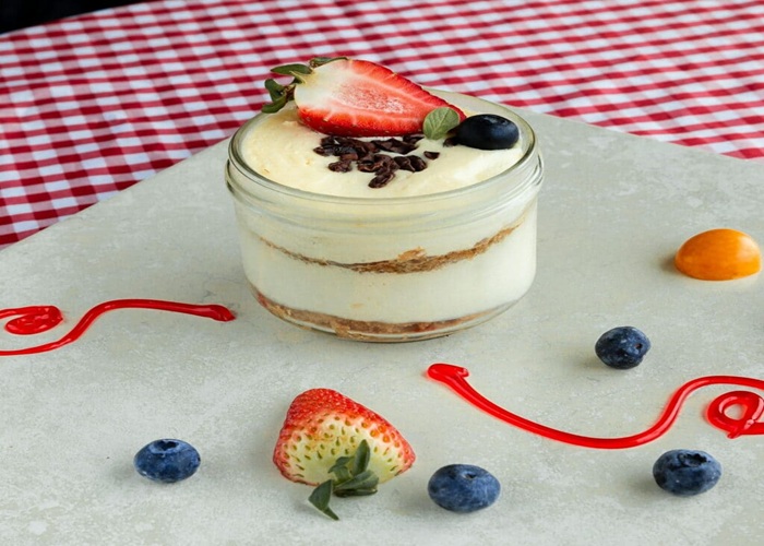 Mousse rosado en copa de cristal decorado con frutos rojos