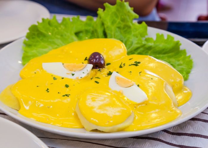 Papas bañadas en crema huancaína saludable con huevo y aceituna